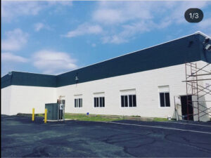 A commercial building exterior freshly painted white and dark green, with scaffolding, by S-G General Contracting LLC in Philadelphia, PA.