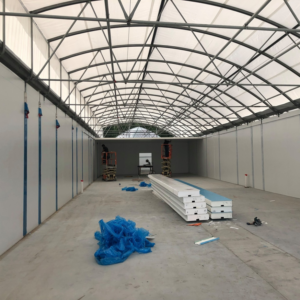 Interior of a commercial building under construction with workers on lifts and SIP panels, by Florida SIP Panels by ACS, Inc. in Tampa, FL