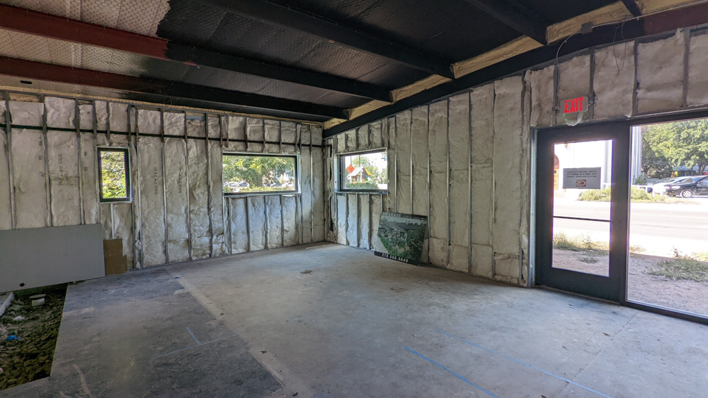Interior of a commercial building under construction with insulated walls and concrete floor by Rivera Services in Chandler, TX.