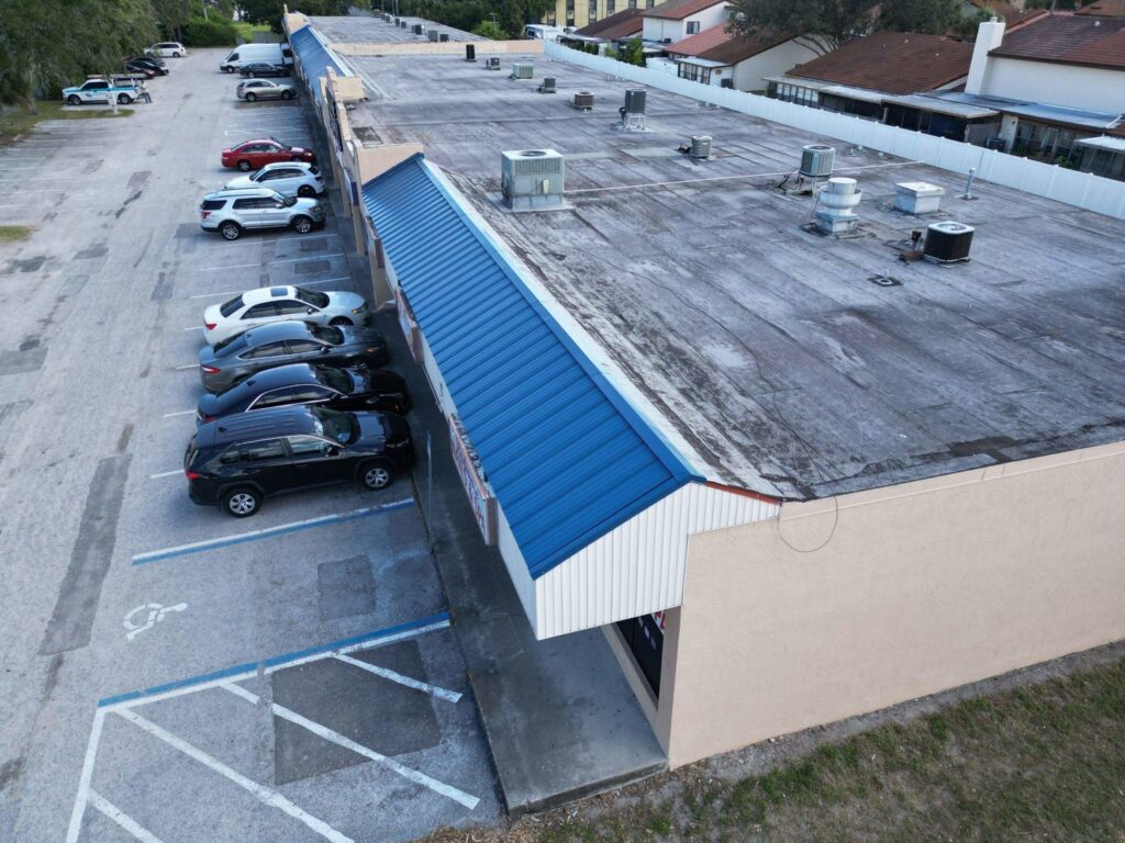 An aerial view of a commercial building with a blue metal awning and flat roof, maintained by Serene Construction, LLC in Richmond, VA.