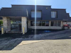 Exterior of a commercial building with a stone facade and dark roof, a project by Austin Roofing and Construction in Austin, TX.