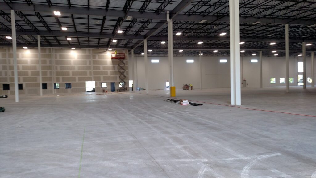 An interior view of a commercial building under construction, showing drywall and a scissor lift, by Valiant Electric Inc. in Kenosha, WI.