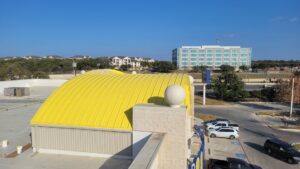 Commercial building with a distinctive yellow roof by Painting Professionals, Inc. in Houston, TX