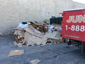 A large pile of cardboard boxes and commercial debris next to a Junk King Plano, TX truck for removal.