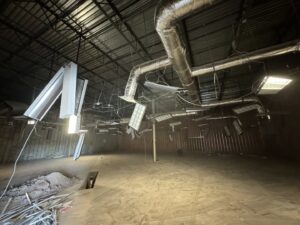 An empty commercial space after demolition with hanging fixtures and debris, showing cleanup services by HAVOC Demolition in Scottsdale, AZ.
