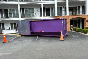 A purple dumpster from JP's Disposal Inc. placed in a commercial parking lot with cones in Hampton, VA.