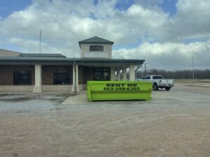 A bright green dumpster placed for commercial junk removal services by Tristate Dumpsters LLC in Greenville, MS.