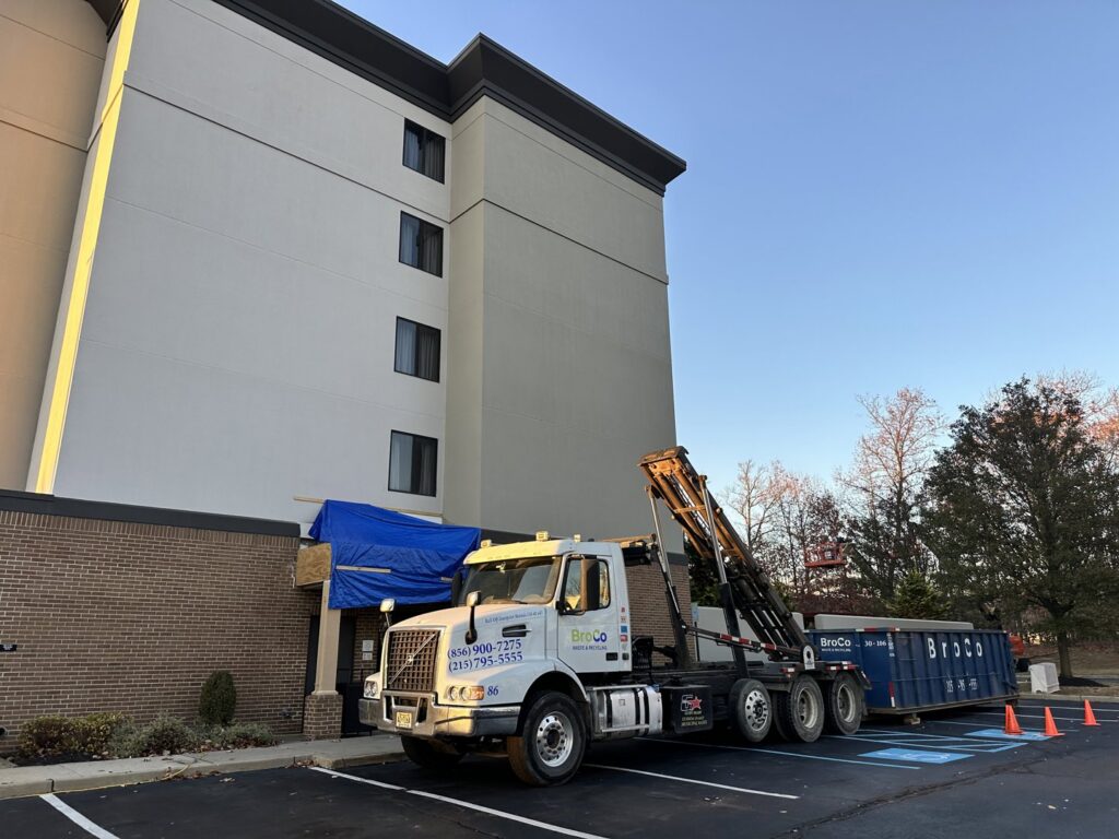 A Broco Waste & Recycling truck with a dumpster providing service at a commercial building in Warminster, PA.