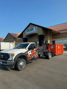Red River Removal truck with a roll-off dumpster providing commercial service in West Fargo, ND.