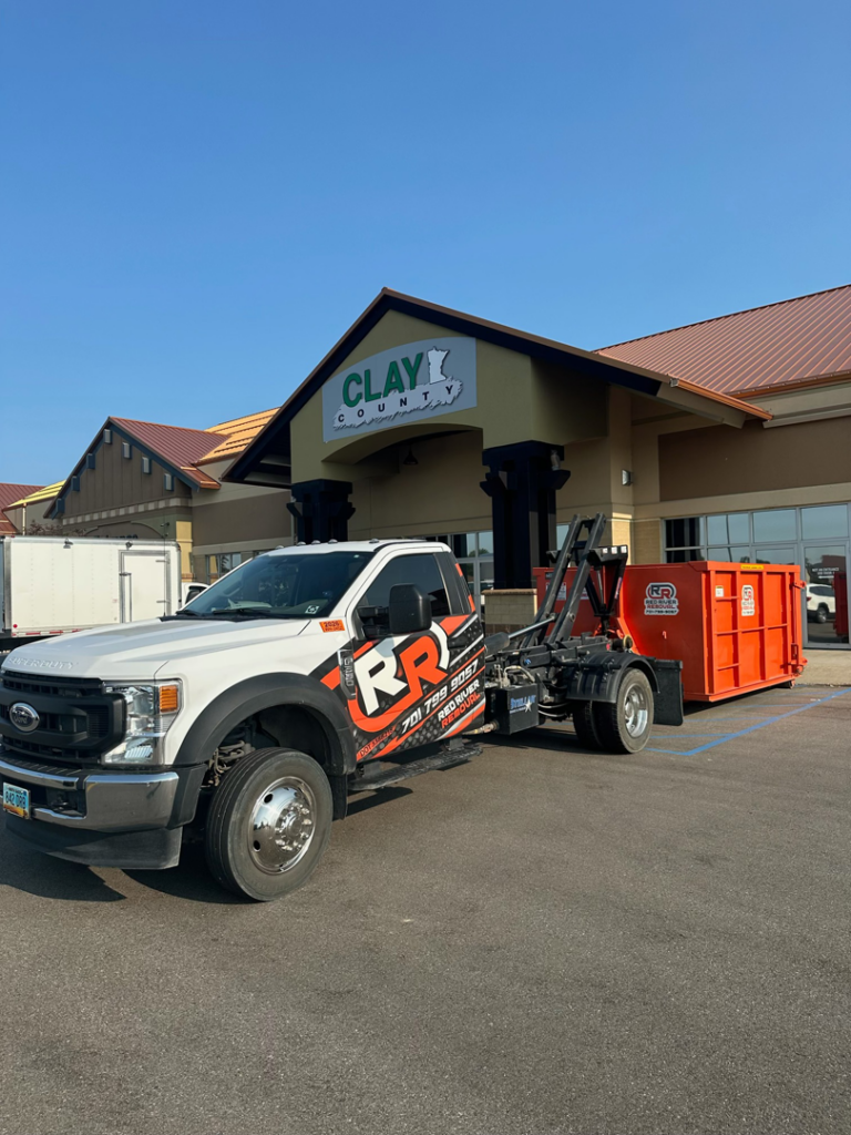 Red River Removal truck with a roll-off dumpster providing commercial service in West Fargo, ND.