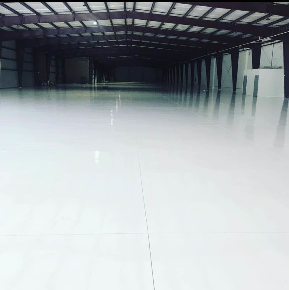 A large commercial space with newly installed shiny white epoxy flooring by Catalyst Contracting in Cape Coral, FL.