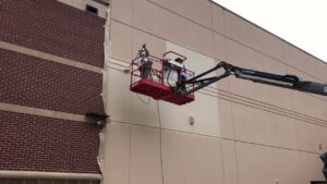 Commercial exterior building painting with a boom lift by Painting Professionals, Inc. in Houston, TX
