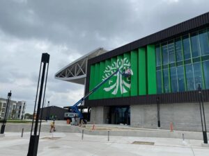 A worker on a boom lift performing commercial exterior painting on a large building for T-Byrd Painting in Austin, TX