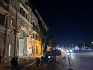 Commercial exterior renovation work at night with a boom lift and Ricos Renovations signage in Arlington, TX