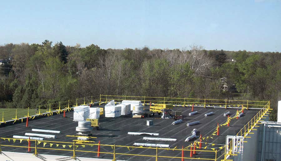 A commercial flat roof under construction with materials and safety railings by RHI Construction Inc in Philadelphia, PA.