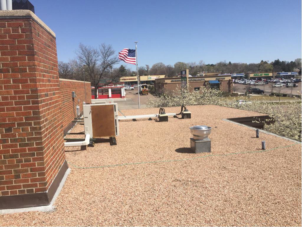 A commercial flat roof with HVAC units and an American flag, maintained by Elite Roofing Colorado Springs, CO.