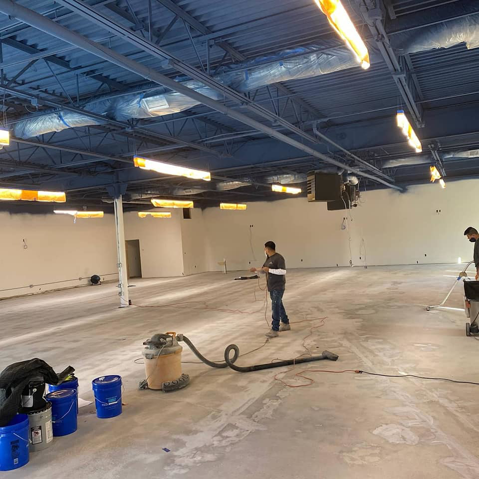 Handyman team cleaning a large commercial concrete floor with industrial vacuums for Desired Finishes in Ann Arbor, MI