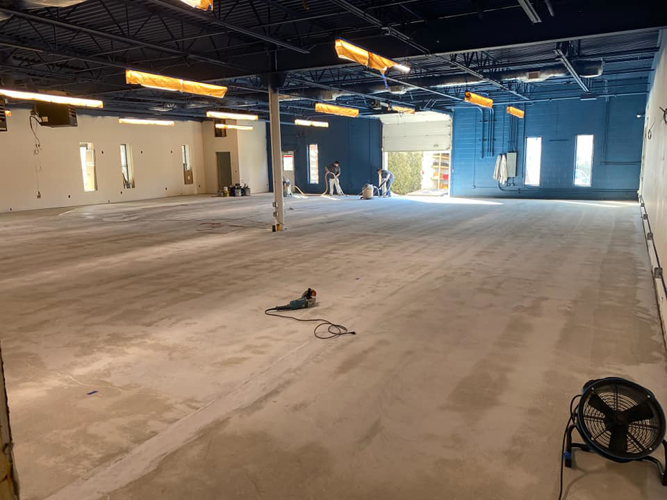 Workers preparing a large commercial concrete floor for finishing at a Desired Finishes project in Ann Arbor, MI