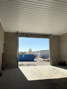 An open commercial garage door bay at a construction site, showing work in progress by Gateway Door and Contracting in House Springs, MO.