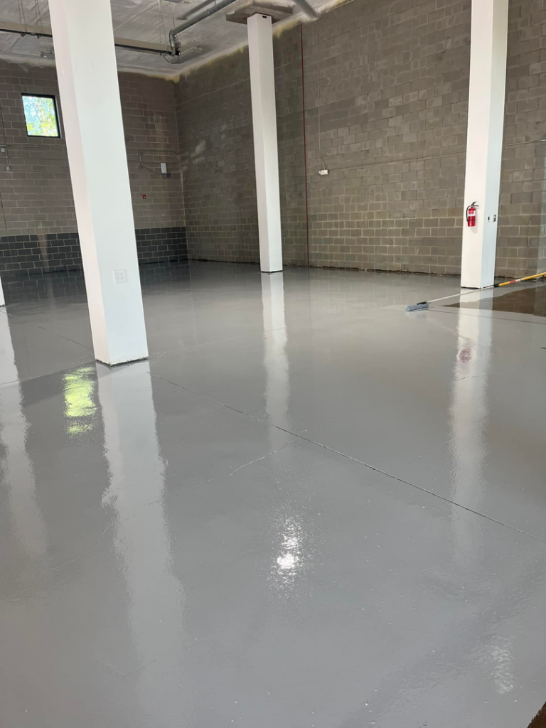 A newly applied grey epoxy floor coating in a large commercial space by Quality Painting of Raleigh in Raleigh, NC.