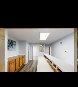 A long commercial hallway or room with new light blue paint, flooring, and built-in cabinetry by EJ Drywall Plus in Kearney, NE.