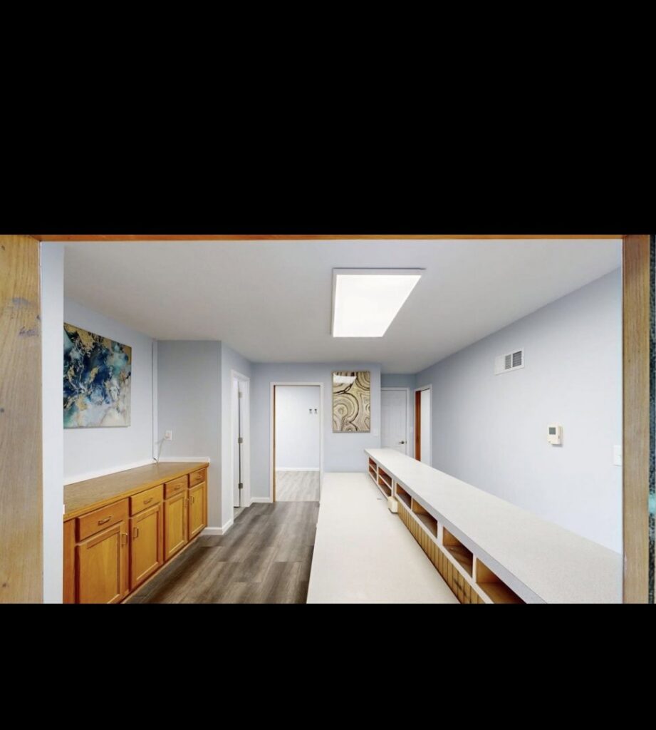 A long commercial hallway or room with new light blue paint, flooring, and built-in cabinetry by EJ Drywall Plus in Kearney, NE.