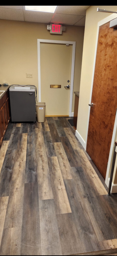 A commercial hallway with new wood-look flooring and a door with a mail slot installed by Leupitz Contractors Inc in Salem, OR.