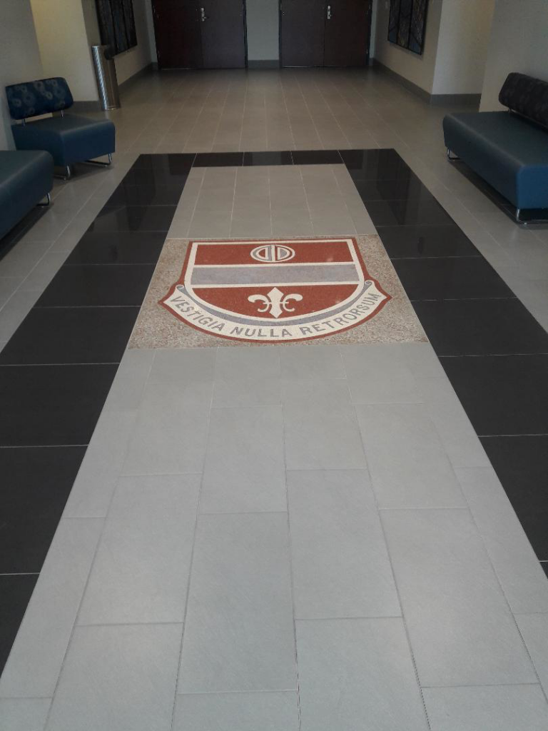 Commercial hallway with custom tile flooring and a decorative crest by Guaranteed Installations in Tampa, FL.