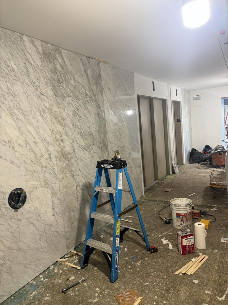 A commercial hallway undergoing renovation with a ladder and materials by Golden Tile Construction in Yonkers, NY.