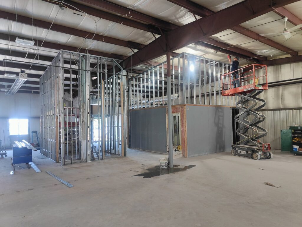 A worker on a scissor lift installing metal framing in a commercial interior renovation by NED CO. in Springfield, MA.