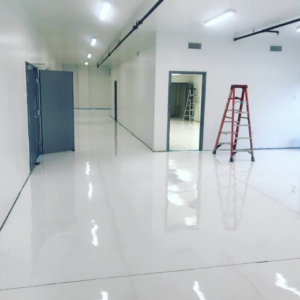 A newly renovated commercial interior hallway with bright white floors and walls by Catalyst Contracting in Cape Coral, FL.
