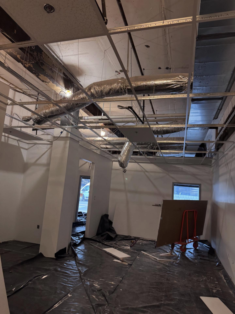 An interior commercial space undergoing renovation with an exposed ceiling, ductwork, and floor protection by Russell General Contracting, LLC in Pittsburgh, PA.