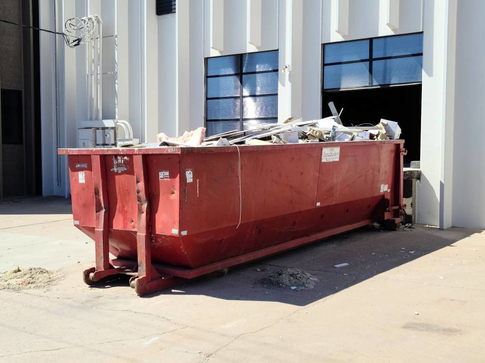 A red dumpster filled with commercial junk and debris for removal by Trash Daddy in Fort Worth, TX