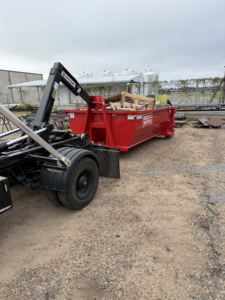 A Boxx Boss Solutions dumpster filled with wood debris at a commercial site for junk removal in Bossier City, LA.