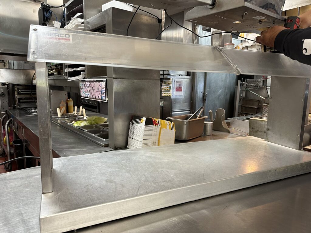 A handyman installing a metal shelf in a commercial kitchen, performed by Prospective 1, LLC in Sparks, NV.