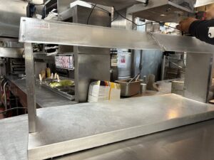 A handyman installing a metal shelf in a commercial kitchen, performed by Prospective 1, LLC in Sparks, NV.