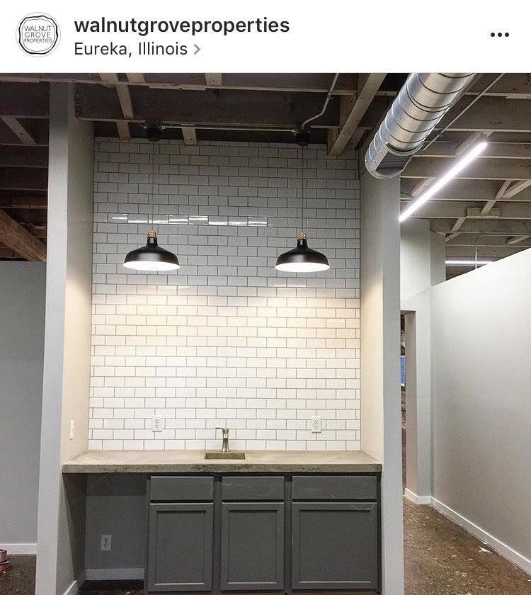 A newly renovated commercial kitchenette with subway tile and pendant lights by Failsafe Electric, Inc. in Metamora, IL.
