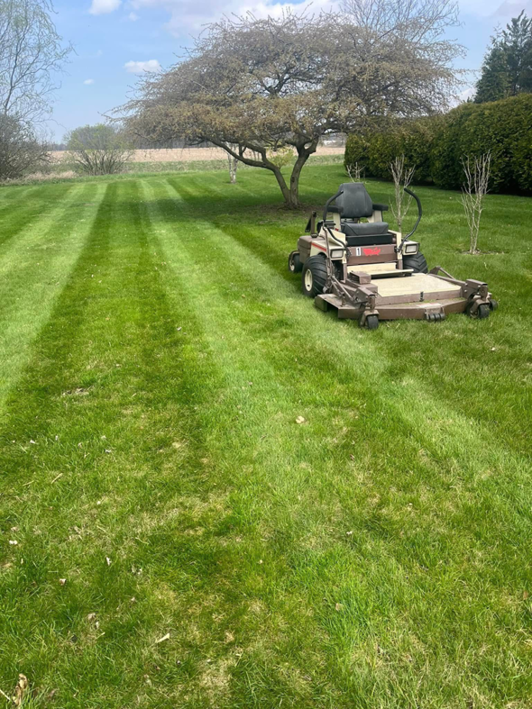 A commercial lawnmower creating striped patterns on a well-maintained lawn by E&K Property Preservation in Lake, MI.