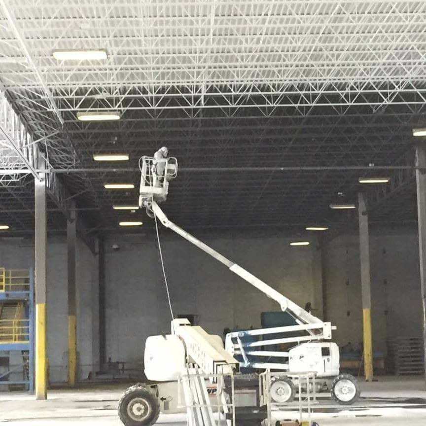 A worker in a boom lift performing commercial lighting repair for Chavez Contractor, LLC in St. Louis, MO.