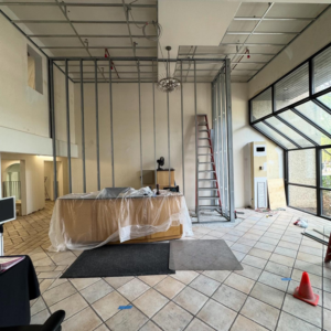A commercial lobby under construction with metal framing and a ladder by Markos Construction in Cambridge, MA.