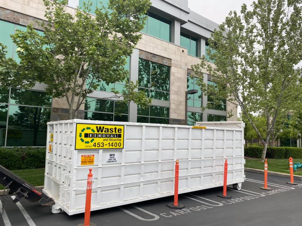 A large roll-off dumpster positioned outside a commercial office building for business cleanout by Waste Removal and Recycling in Sacramento, CA.