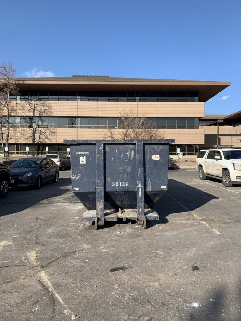 A large blue dumpster placed in a commercial parking lot, ready for general junk removal services from Discount Dumpster in Naples, FL.
