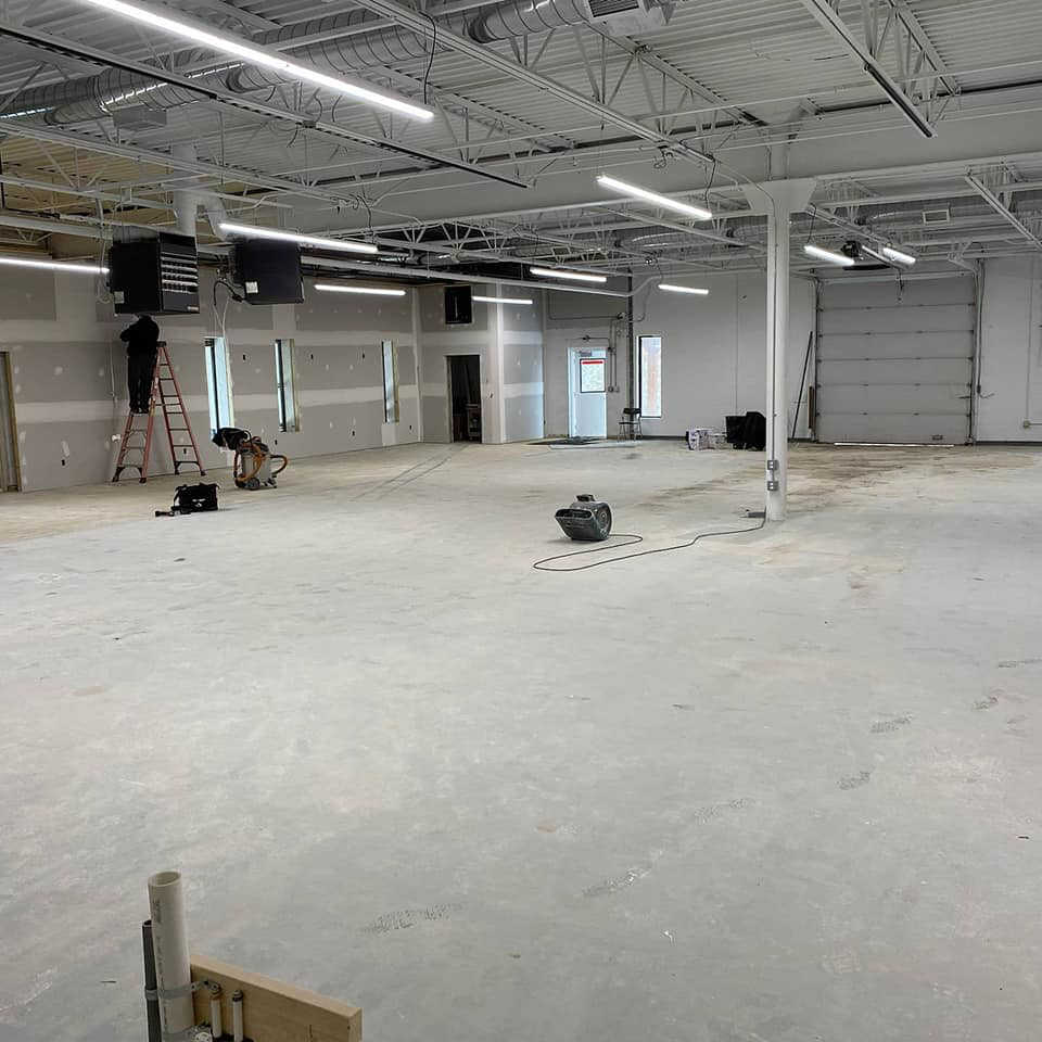 Commercial space under renovation with drywall installed and workers on ladders for Desired Finishes in Ann Arbor, MI