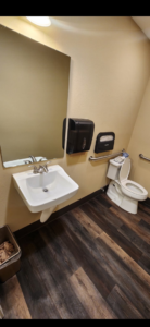 A commercial restroom featuring a wall-mounted sink, mirror, and grab bars installed by Leupitz Contractors Inc in Salem, OR.