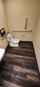 A commercial restroom with a toilet, grab bars, and new flooring installed by Leupitz Contractors Inc in Salem, OR.