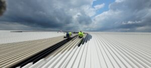 Workers applying a protective coating to a large commercial roof, a service provided by T-Byrd Painting in Austin, TX