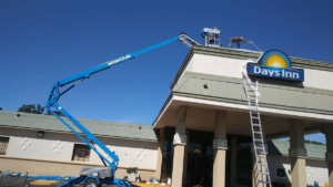 Workers on a boom lift performing commercial roof repair or maintenance at a Days Inn hotel by Barrios Remodeling in Kansas City, MO.