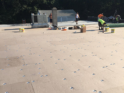 Workers installing a new commercial flat roof, demonstrating expert roofing services by Elk Building Services in Toledo, OH.