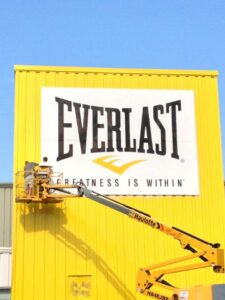 Workers on a boom lift installing a large commercial sign on a building by CMFM Construction in Columbia, MO