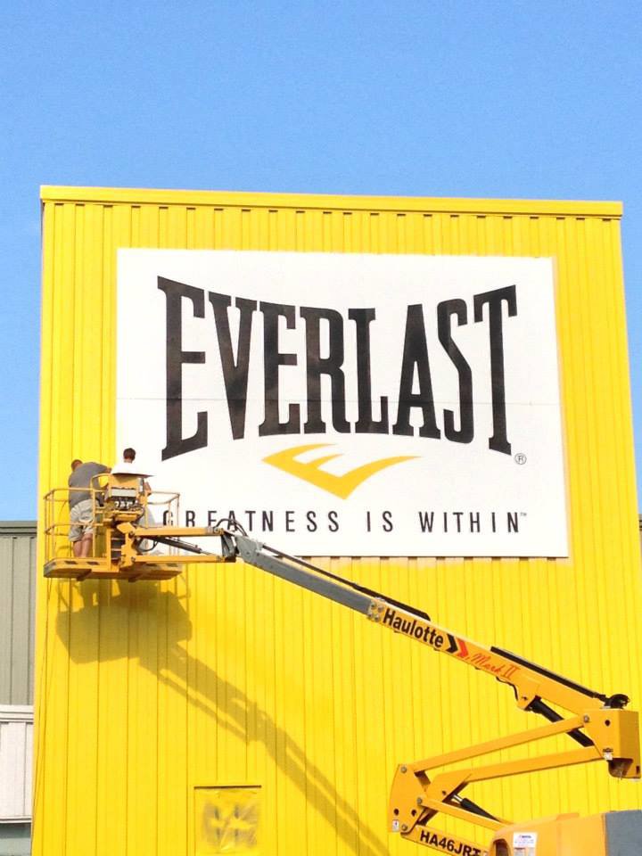 Workers on a boom lift installing a large commercial sign on a building by CMFM Construction in Columbia, MO
